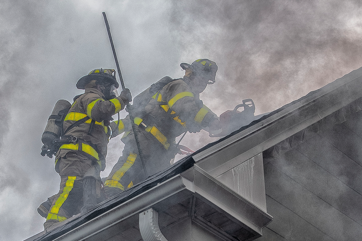 Image of fire fighters fighting the fire on a house roof.